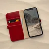 A red leather iPhone case with card slots is open, showing a credit card and cash, with an iPhone displaying a mountain landscape inside. Produktbild-Vorschau