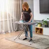 A woman is ironing clothes on an ironing board in a living room. Produktbild-Vorschau
