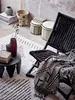A cozy corner with a black woven chair, a patterned rug, and decorative items. Náhľad obrázku produktu