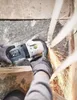 A person wearing work gloves is using an angle grinder to cut a metal pipe, creating sparks. Produktbild-Vorschau