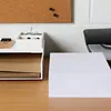 A desk with office supplies, including paper, a tray with clips, and a corkboard in the background. Náhled obrázku produktu