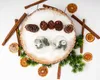 Christmas-themed arrangement with pine cones, cinnamon sticks, dried oranges, and greenery on a wooden slice dusted with artificial snow. Podgląd zdjęcia produktu