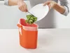 A person is shown discarding food scraps into an orange trash can. Podgląd zdjęcia produktu