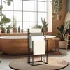 A modern bathroom with a wooden bathtub, plants, and a black metal towel rack. Produktbild-Vorschau