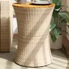 A beige poly rattan side table with a wooden top, placed on a balcony next to a large potted plant. Produktbild-Vorschau