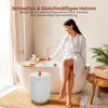 A woman in a white robe sits on the edge of a bathtub, with a white bucket-style towel warmer next to her. Podgląd zdjęcia produktu