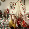 Three young girls are playing inside a teepee decorated with Christmas lights and pom-pom garlands. A small, flocked Christmas tree is also decorated with pom-pom garlands. Produktbild-Vorschau