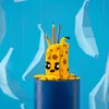 A yellow LEGO octopus pencil holder with pencils in it, sitting on a blue cylinder, with blue paper decorations in the background. Podgląd zdjęcia produktu