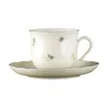 A cream-colored coffee cup and saucer with a floral pattern and blue trim, set against a white background. Produktbild-Vorschau