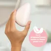 A hand holding a pink, egg-shaped hair removal device with a pink circle containing a feather icon and German text overlaid on the right side. Anteprima dell’immagine prodotto