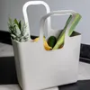 A light gray Koziol shopping bag filled with fruits and vegetables, placed on a black and white checkered floor. Náhled obrázku produktu