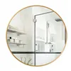 A round mirror with a gold frame reflecting a modern bathroom interior. Produktbild-Vorschau