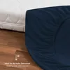 A close-up view of a dark blue fitted sheet draped over a white mattress, with a wooden floor in the foreground. Voir les images du produit