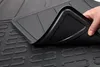 A hand is lifting a corner of a black rubber car mat, showing its textured surface and raised edges. Produktbild-Vorschau