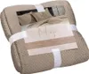 A folded beige quilted blanket with a product label. Podgląd zdjęcia produktu