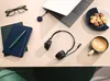 A desk setup with a laptop, headphones, notebooks, glasses, coffee, and cookies. Náhled obrázku produktu