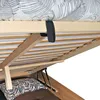 A close-up view of the underside of a wooden bed frame, showing the slatted base and storage lift mechanism. Produktbild-Vorschau