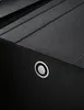 A close-up of a black sink with a silver circular button. Produktbild-Vorschau