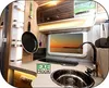 Interior of a camper van kitchen with a sink, faucet, and window showing a sunset. Produktbild-Vorschau