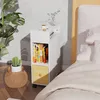 A bedside table with books, a plant, and a cup of coffee next to a bed. Voir les images du produit