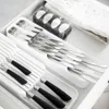 A drawer organizer for cutlery with multiple compartments holding silverware and a small packaged item. Anteprima dell’immagine prodotto