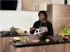 A woman is in a kitchen preparing food. Voir les images du produit