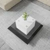 A modern coffee table with a white cube base and layered glass tops, placed on a rug in a living room setting. Voir les images du produit
