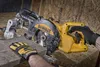 A person wearing work gloves is operating a yellow and black Dewalt miter saw on a wooden surface. Náhľad obrázku produktu