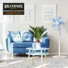A living room scene with a blue sofa, a plant, and a white stand fan. Anteprima dell’immagine prodotto