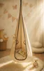 A child's hanging chair in a cozy, softly lit room with decorative elements. Produktbild-Vorschau