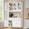 A white kitchen sideboard with glass doors, filled with kitchen items, placed in a kitchen setting. Náhled obrázku produktu