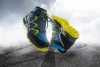 Two hiking boots are shown floating in the air above a road with tire tracks. Produktbild-Vorschau