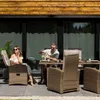 A couple enjoying drinks at a table on a patio with a wooden building in the background. Náhled obrázku produktu