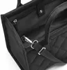 A close-up view of the interior and strap attachment of a black quilted tote bag. Voir les images du produit