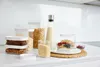 A collection of food storage containers filled with various dry goods and some fruit, arranged on a kitchen counter. Náhľad obrázku produktu
