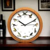 A clock with bird illustrations on a wooden table. Produktbild-Vorschau