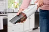 A person is holding a handheld vacuum cleaner in a kitchen. Produktbild-Vorschau