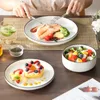 A person is eating a meal consisting of salmon, vegetables, and a dessert, with a salad and a drink on the side. Náhled obrázku produktu