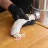 A person wearing black gloves is stuffing a sausage casing with meat using a sausage stuffer. Produktbild-Vorschau