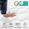 A hand pressing into a white mattress, with certification logos and feature icons displayed. Produktbild-Vorschau