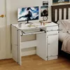 A white computer desk with a monitor, keyboard, and a mug, placed next to a bed in a bedroom. Podgląd zdjęcia produktu