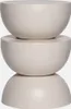 A stack of three rounded objects, resembling bowls or tables, in a creme color against a light gray background.