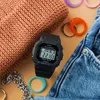 A flat lay of a black Casio Baby-G watch surrounded by various accessories like rings, a bracelet, and denim fabric. Produktbild-Vorschau