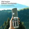 A hand holding a portable coffee maker in a mountainous, forested landscape. Produktbild-Vorschau