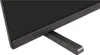 A close-up shot of the bottom corner and stand of a black television. Náhled obrázku produktu