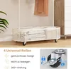 A white perforated basket on wheels, with a clothing rack and a dresser in the background. Náhled obrázku produktu