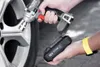 A person is holding a cordless impact wrench and a battery pack next to a car wheel. Produktbild-Vorschau