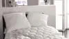 A neatly made bed with two pillows and a comforter. Produktbild-Vorschau