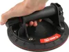 A hand holding a black suction cup lifter with a red trim and a red and white logo. Produktbild-Vorschau