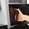 A hand is shown inserting a brown component into a coffee machine. Produktbild-Vorschau